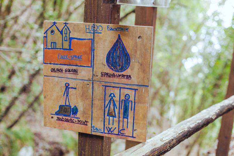 Signpost in the woods, showing spring water and toilets. Sentiero degli Dei