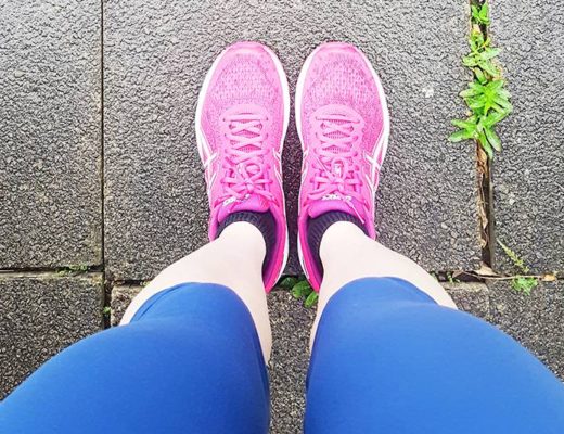 Woman's legs wearing blue running leggings and pink trainers